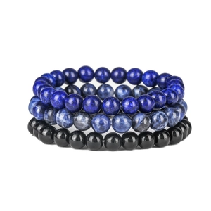 Detailed stack of rose quartz and black onyx beaded yoga bracelets on white background