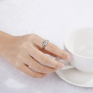 Bague chevalière argentée polie avec motif étoile portée sur fond en peluche blanc
