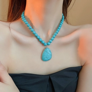 Detail of bohemian turquoise beaded necklace with cracked teardrop pendant on female model