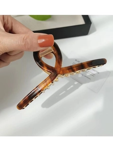 Detail of tortoise shell acetate hair claw clip with golden metal teeth for high-end styling