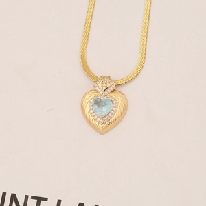 Macro shot of gold heart pendant featuring a light blue stone and pave crystals