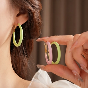 Detail of round enamel hoop earrings in light green and soft pink with metal clasp