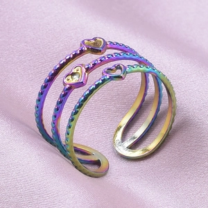 Detail shot of a rainbow-plated triple-layer heart ring on pink silk fabric background