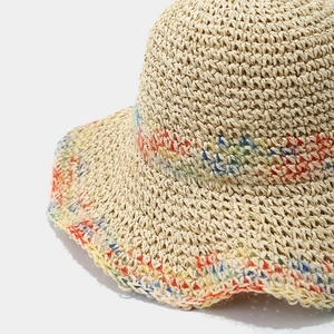 Detailed macro view of colorful fiber weaving on a beige straw sun hat with wavy brim