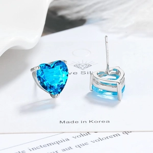 Close-up of heart-shaped blue zircon earrings with silver four-prong setting