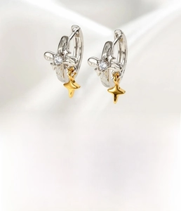 Macro detail of silver ear hoop with gold star pendant and sparkling cubic zirconia