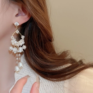 Elegant floral drop earrings with white crystals and pearls on a model portrait