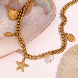 Detailed close-up of 18K gold plated starfish, shell and pearl charms on a necklace