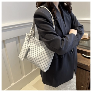Model wearing a large vintage printed white shoulder bag in a stylish cafe setting