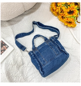 Close-up of deep blue denim shoulder bag with front pocket on white lace background