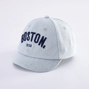 Detailed view of light blue denim baby baseball cap with navy Boston 1630 embroidery