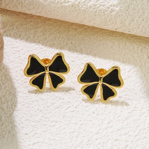 Gros plan de boucles d'oreilles nœud noir bordées d'or sur pierre blanche