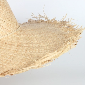 Close-up of natural woven raffia straw hat showing detailed texture and fringe edge
