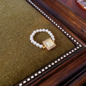Macro shot of 18k gold plated square gemstone ring with pearls on a vintage tray
