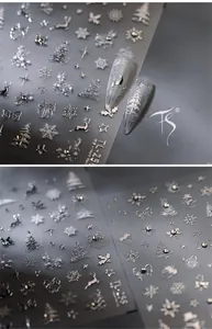 Macro detail of 3D metallic silver Christmas nail stickers with reindeer and snowflake patterns