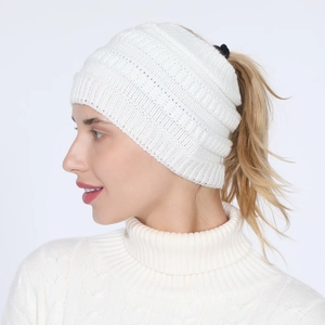 Detail of white knitted headband with ponytail hole showing warm winter texture