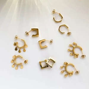 Detailed view of polished gold geometric hoop earrings and round disc stud jewelry set