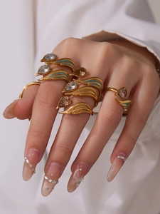 Detail of gold stacking rings with blue enamel wing design and teardrop crystal stones