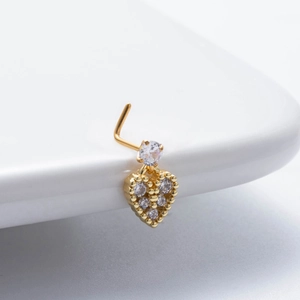 Close-up of golden L-shaped nose stud featuring a sparkling zircon heart pendant