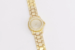 Detailed close-up of golden quartz watch with full rhinestone inlay and luxury hip hop style