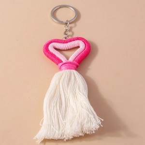 Macro view of handmade knit heart keychain with pink and white tassels and metal ring