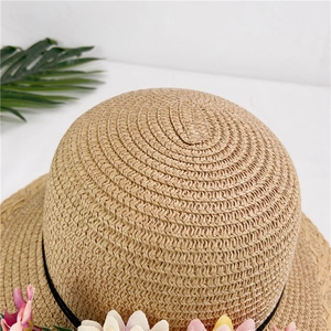 Close-up of woven straw hat with vibrant floral decorations and black ribbon trim
