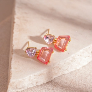 Macro shot of geometric earrings featuring purple triangle and pink trapezoid crystals