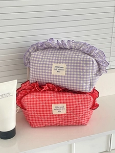 Detail of quilted berry-colored cosmetic bags with ruffled edges and fabric labels