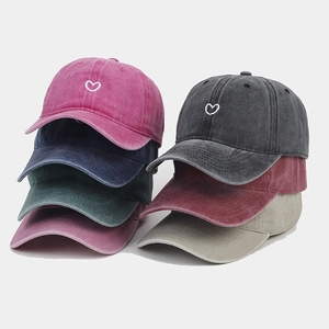 Multiple vintage washed baseball caps with embroidered heart logos in various colors