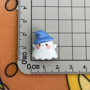 Macro shot showing small white ghost resin charm with blue hat measuring about 2cm