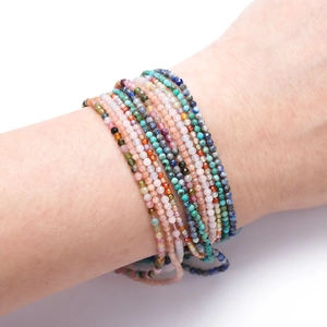Close-up of stacked 2mm faceted natural stone bead bracelets on a model's wrist