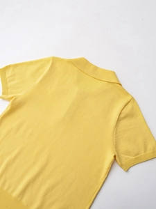 Detail of a yellow short sleeve knit polo shirt showing fine texture and ribbed hem