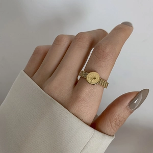 Detailed close-up of gold mesh band ring featuring an Elizabeth II coin on a model's finger