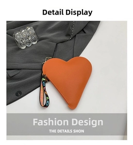 Détail du sac coeur en cuir orange avec dragonne tissée portant le mot LOVE
