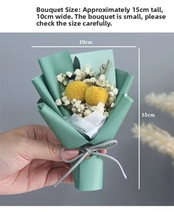 Handheld mini bouquet featuring yellow craspedia and white babysbreath in green paper