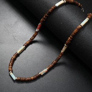 Detail of coconut shell beaded necklace with natural stone accents on dark surface