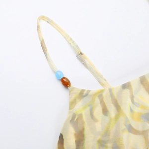 Detailed close-up of adjustable strap with blue and amber beads on printed summer dress