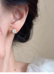 Close-up of elegant gold square diamond stud earring worn by a model in soft natural light