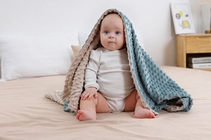 Dettaglio del tessuto minky blu a pois e morbida fodera beige per una coperta da neonato
