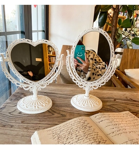 Close-up of vintage white heart and oval vanity mirrors with ornate relief carving details