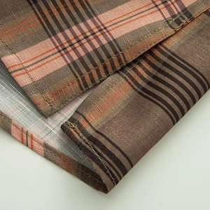 Detailed macro view showing the brown and orange plaid fabric texture and double stitching