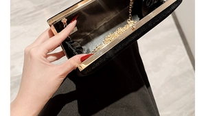 Detailed close-up of a black velvet clutch bag with gold metal frame and chain strap