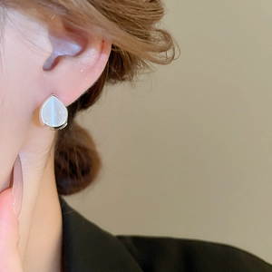 Side close-up view of silver teardrop cat eye stone earrings worn by a model