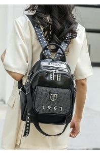 Detail of black faux leather backpack with silver zippers, rhinestones and logo patch