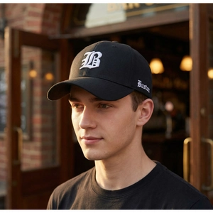 Detailed close-up of white Gothic B embroidery on black cotton baseball cap