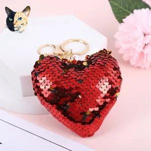Detail of red sequined heart keychain with golden lobster clasp on pink background