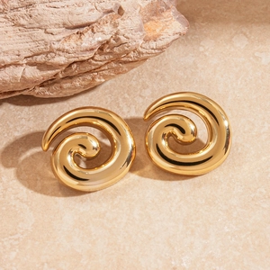 Detailed view of golden spiral stud earrings on natural textured stone background