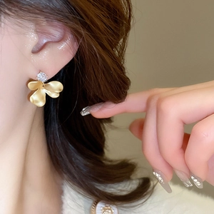 Macro view of gold flower earrings with matte petals and sparkling cubic zirconia stones