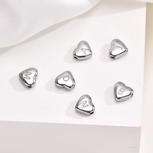 Macro view of heart-shaped stainless steel letter charms with A, J, M, Q, B, Z engravings
