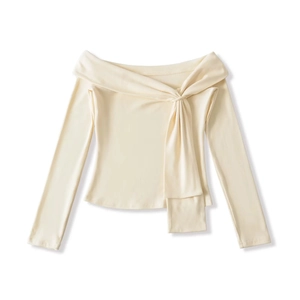 Detail of cream off-shoulder top with elegant twisted neckline and soft knit texture